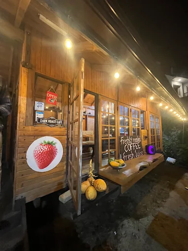 Dark Roast Café's wooden cabin at night, lit by string lights